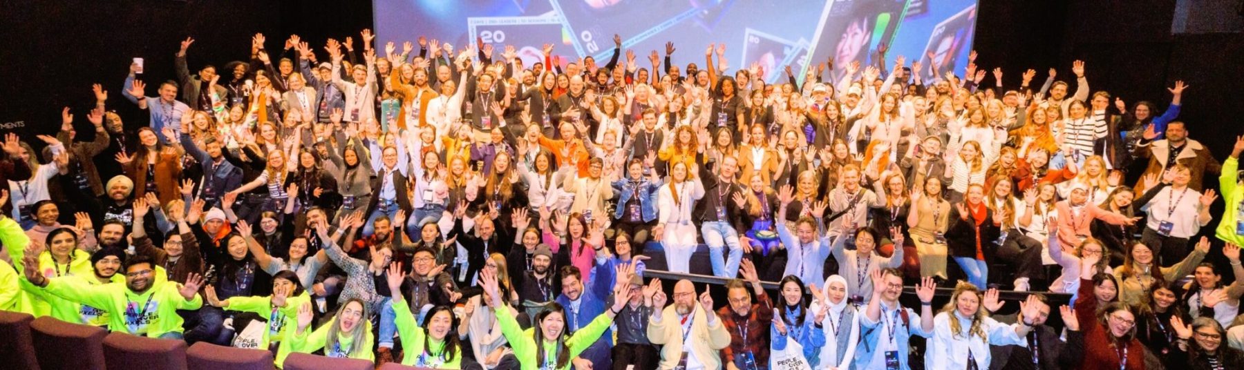 Hundreds of participants with hands raised at a leadership summit